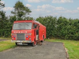 A red fire truck parked in a field at Dashing Dennis - 22 in Chapmanswell near Launceston