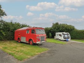 A red truck and a caravan parked on grass at Dashing Dennis - 22 Chapmanswell near Launceston