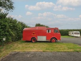 A red fire truck and a caravan parked on a grassy area at Dashing Dennis - 22 Chapmanswell near Launceston