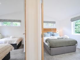 A bedroom with two beds and windows at 3 Meadow Retreat in Liskeard