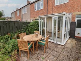 A garden with a table and chairs next to a conservatory at 5 Jackson Terrace Morpeth
