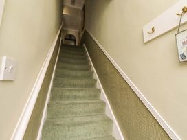 A staircase with green carpet and wall decor at Rose Briar Cottage in Morpeth