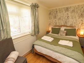 A bedroom with a bed, bedside table and window at Rose Briar Cottage in Morpeth
