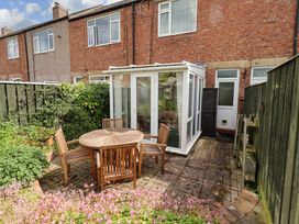 A garden with a conservatory and a table with chairs at Rose Briar Cottage Morpeth