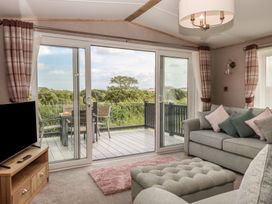 A living room with a sofa and television at Maple Lodge Teigngrace near Kingsteignton