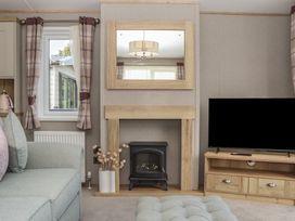 A living room with a fireplace and television at Maple Lodge Teigngrace near Kingsteignton