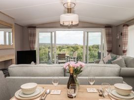 A living room with a view of the outdoor seating area at Maple Lodge in Teigngrace near Kingsteignton
