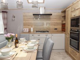 A kitchen with a dining area, stove, and cabinets at Maple Lodge Teigngrace near Kingsteignton