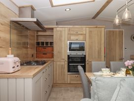 A kitchen with cabinets and dining table at Maple Lodge in Teigngrace near Kingsteignton