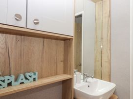A bathroom with a sink and mirror at Maple Lodge Teigngrace near Kingsteignton