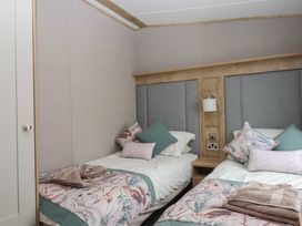 A bedroom with two beds and pillows at Maple Lodge Teigngrace near Kingsteignton