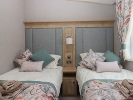 A bedroom with two beds and a bedside table at Maple Lodge Teigngrace near Kingsteignton