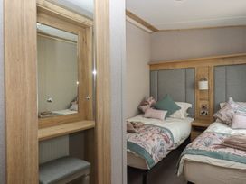 A bedroom with two beds and a mirror at Maple Lodge Teigngrace near Kingsteignton