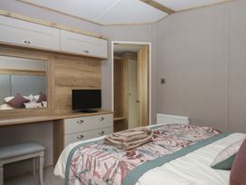 A bedroom with a bed, television, and a mirror at Maple Lodge in Teigngrace near Kingsteignton