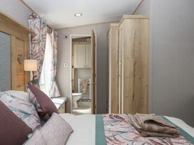 A bedroom with a bed and wardrobe at Maple Lodge, Teigngrace near Kingsteignton