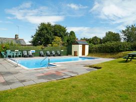A swimming pool surrounded by chairs and a shed at Maple Lodge Teigngrace near Kingsteignton