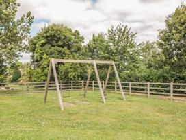 A swing set in a grassy area with trees at Maple Lodge in Teigngrace near Kingsteignton