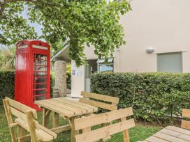 A garden with a telephone box and wooden seating at Maple Lodge Teigngrace near Kingsteignton