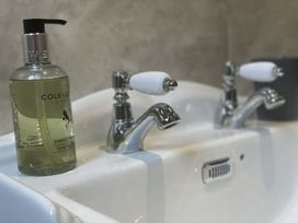 A sink with two faucets and a hand wash bottle at Queensbury Loft in Par