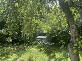 A garden with a table and chairs under an apple tree at Queensbury Loft in Par
