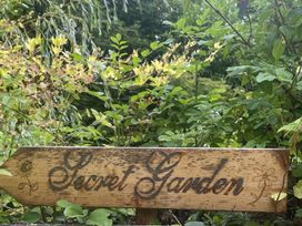 A wooden sign labeled Secret Garden surrounded by plants in a garden at DeCressy Apartment Par