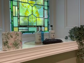 A sink area with toiletries and a stained glass window at Garden Apartment in Par
