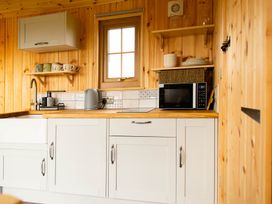A kitchen with cabinets and appliances at Head For the Hills Glamping - Skylark Shepherd's Hut