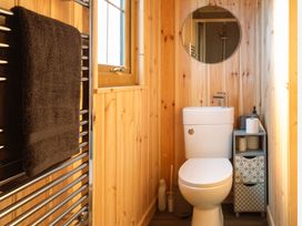 A bathroom with a toilet, towel rack, mirror, and sink at Head For the Hills Glamping - Skylark Shepherd's Hut