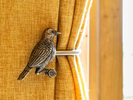 A curtain with a bird tieback at Head For the Hills Glamping - Skylark Shepherd's Hut