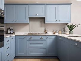 A kitchen with blue cabinets and a stove at Lavender Cottage (Stow-on-the-Wold) Cheltenham