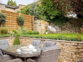 A garden with a table and chairs near a shed and plants at Lavender Cottage (Stow-on-the-Wold) Cheltenham