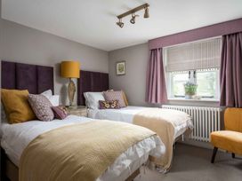 A bedroom with two beds and a chair at Lavender Cottage (Stow-on-the-Wold), Cheltenham