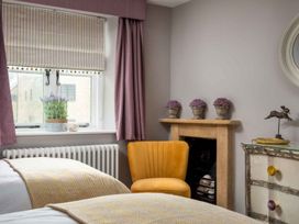 A bedroom with twin beds and a yellow chair at Lavender Cottage (Stow-on-the-Wold) Cheltenham