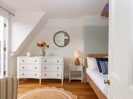 A bedroom with a bed, dresser, and a lamp at The Porthole in Newton Ferrers