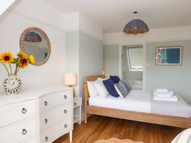 A bedroom with a bed and flowers on a dresser at The Porthole in Newton Ferrers