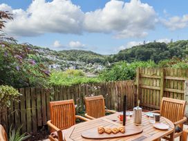 A garden with a wooden table and chairs overlooking a view at The Porthole in Newton Ferrers