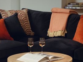 A living room with a sofa, cushions, and a coffee table at The Porthole in Newton Ferrers