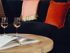 A living room with wine glasses and a book at The Porthole in Newton Ferrers