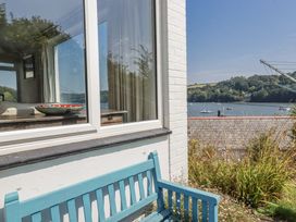 A view of a waterway with boats and houses from an outdoor bench at Kiln Cottage Golant near Tywardreath