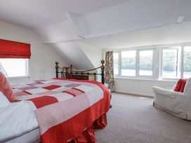 A bedroom with a bed and windows overlooking the water at Kiln Cottage in Golant near Tywardreath