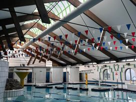 An indoor pool with diving board and decorative flags at Manorcombe 21 in Honicombe Holiday Village near Gunnislake