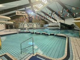 An indoor pool with a water slide and seating area at Manorcombe 21 in Honicombe Holiday Village near Gunnislake