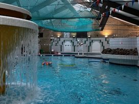 An indoor pool area with a waterfall and floating swimming aids at Manorcombe 21 Honicombe Holiday Village near Gunnislake