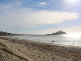A beach with people walking along the shore at Mill House Barn