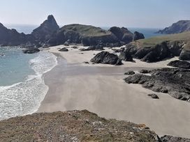A beach with rocks and cliffs in the background at Mill House Barn in 