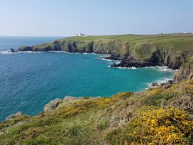 A rocky coastline with a lighthouse at Mill House Barn in 