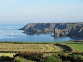 A coastal view with cliffs and a sailing boat at Mill House Barn in 