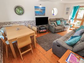 A living room with a dining area and a television at Mill House Barn in Gulval near Penzance