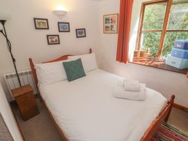 A bedroom featuring a bed and window with framed pictures at Mill House Barn in Gulval near Penzance