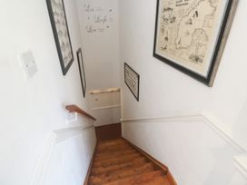A staircase with wooden steps and framed pictures hanging on the wall at Mill House Barn Gulval near Penzance